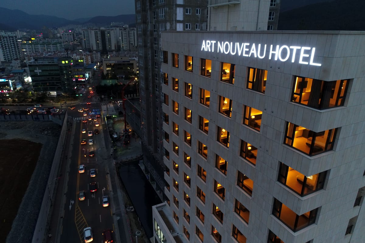 Ein modernes Hotel mit auffälliger Beschilderung, mehreren Stockwerken und einer belebten Straße im Hintergrund.