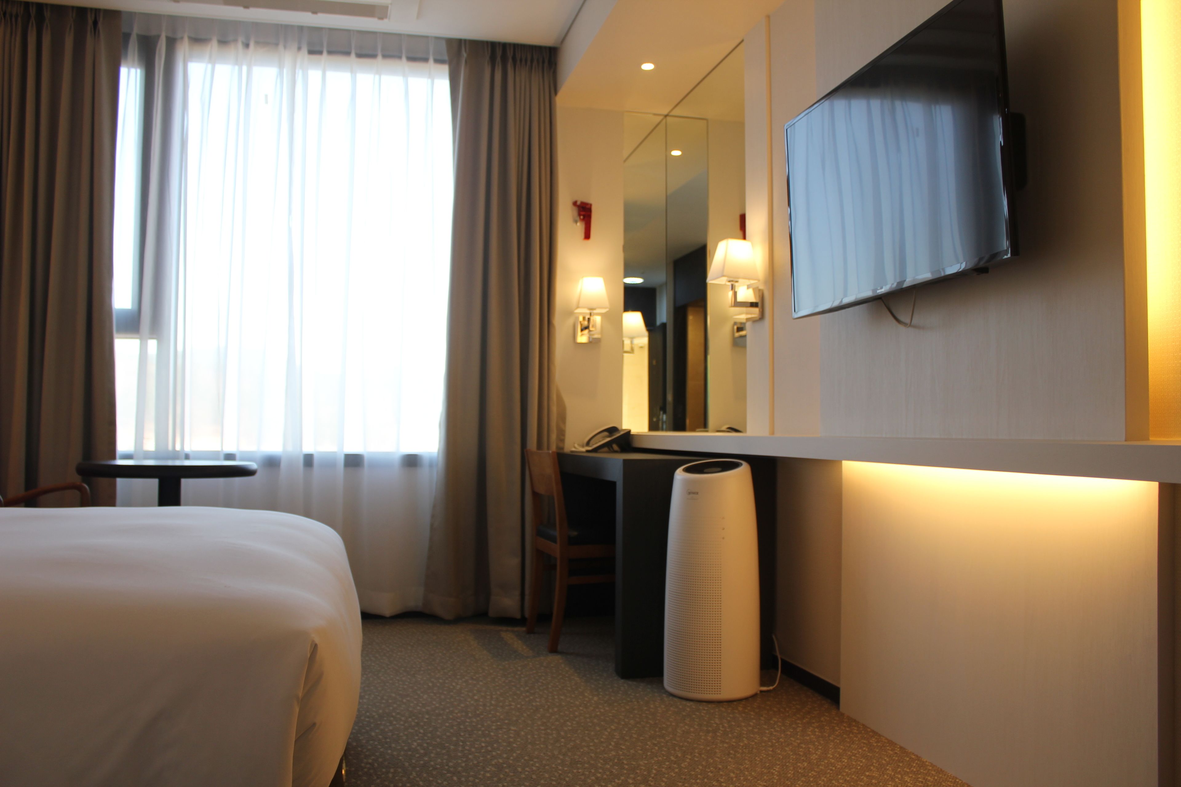 Une chambre d’hôtel avec un lit, un bureau, une chaise, une télévision et une lampe.