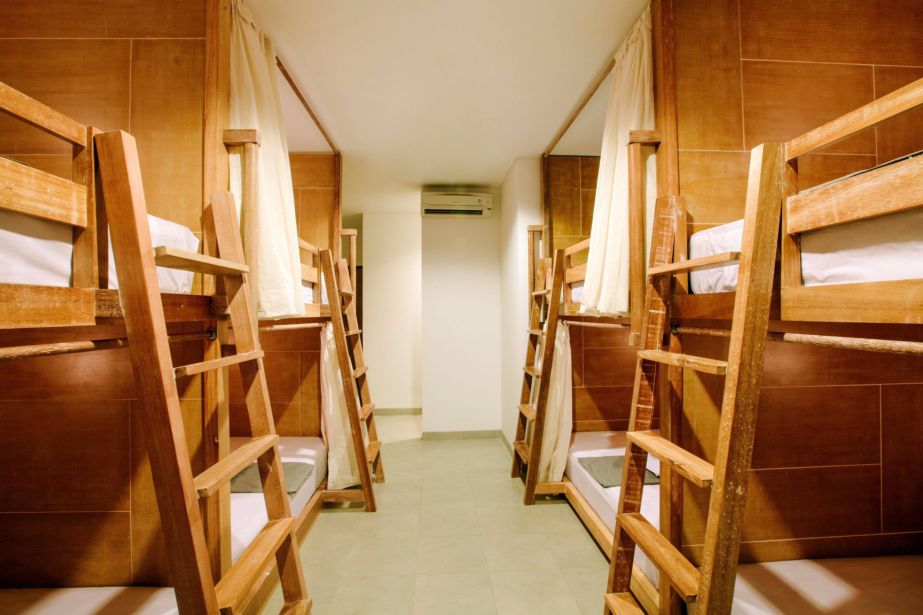 Un pasillo con literas y escaleras de madera que conduce a una habitación con aire acondicionado.