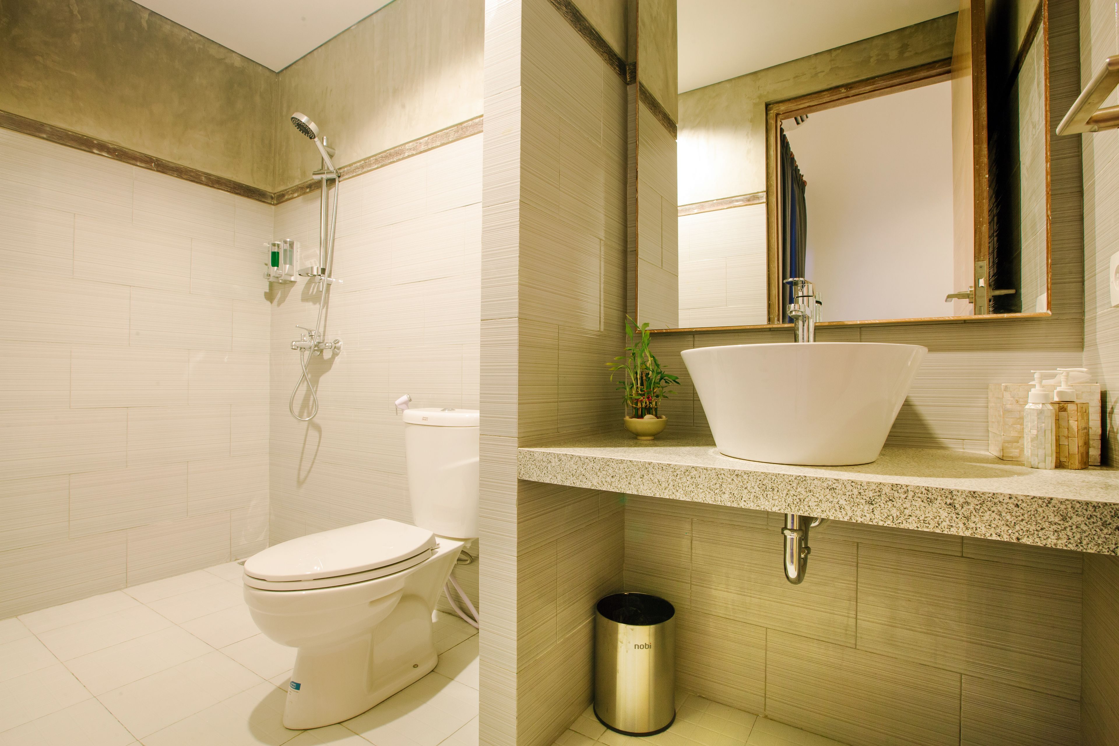 A modern bathroom with a toilet, shower, sink, and mirror.