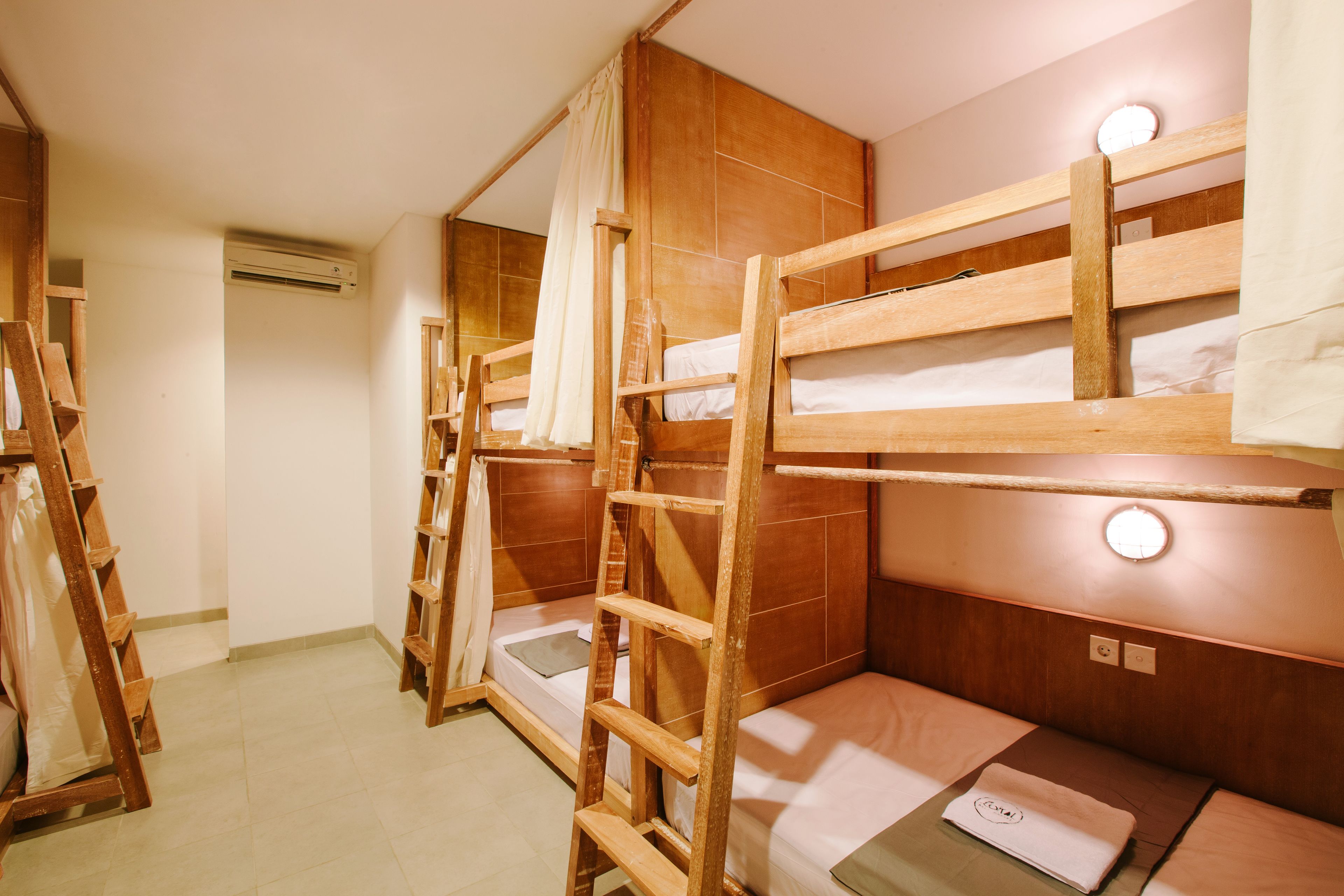 Une chambre de type dortoir, avec des lits superposés, des meubles en bois et une échelle.