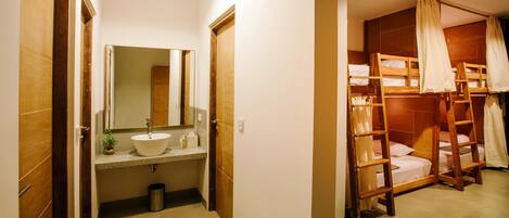 Un baño con lavamanos, espejo y puerta de madera.