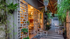 Albergue com entrada em madeira treliçada, degraus de pedra e área de estar ao ar livre.