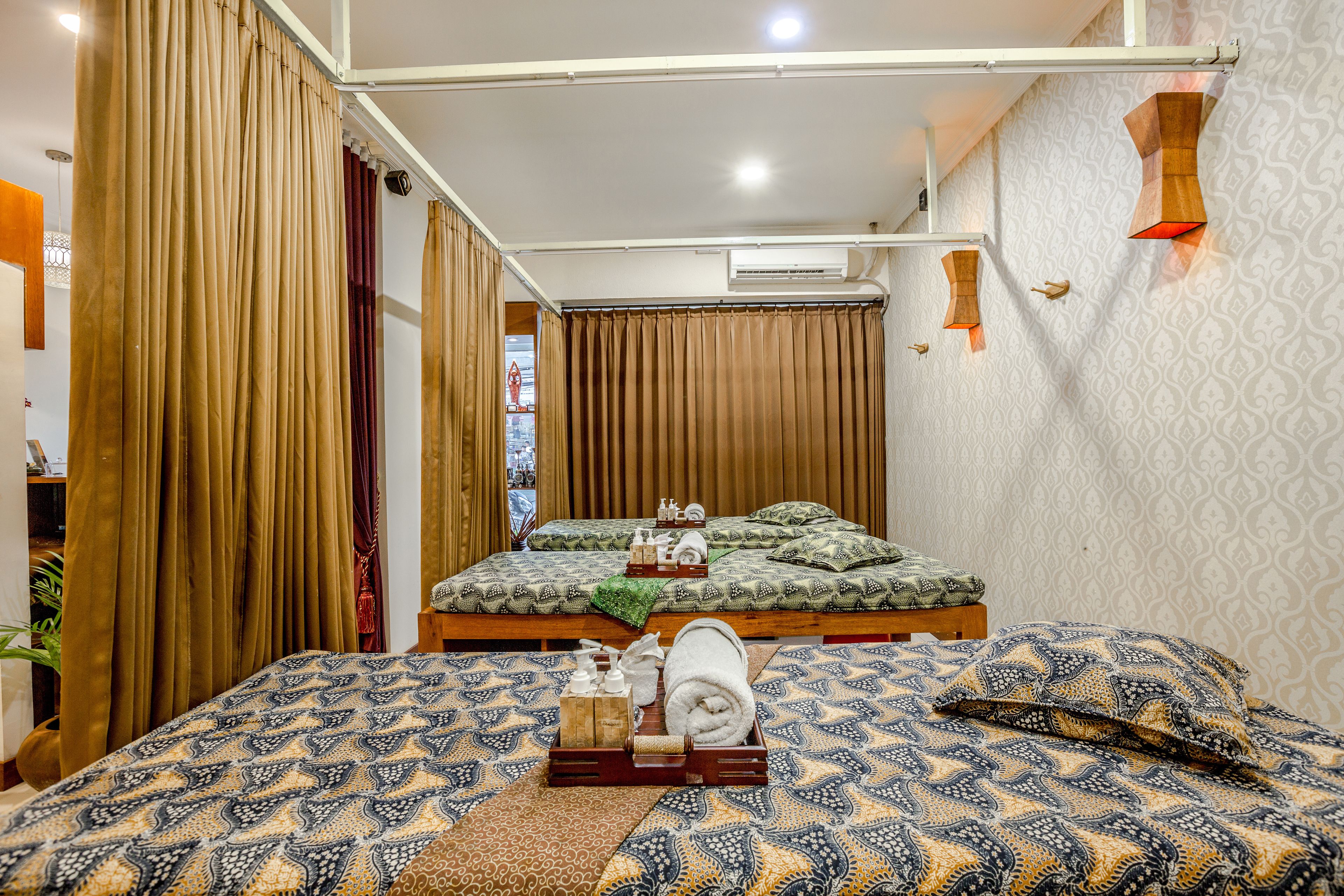 A hotel room with a bed, a small table with toiletries, and a wall-mounted air conditioning unit.
