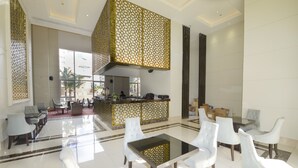 A spacious lobby with a central seating area, a reception desk, and a view of the outside. - Grande Caribbean Hotel Resort Pattaya (Pattaya)