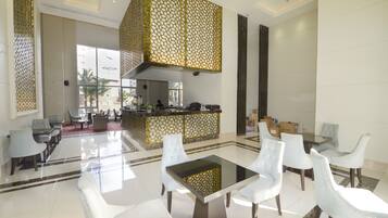 A spacious lobby with a central seating area, a reception desk, and a view of the outside.
