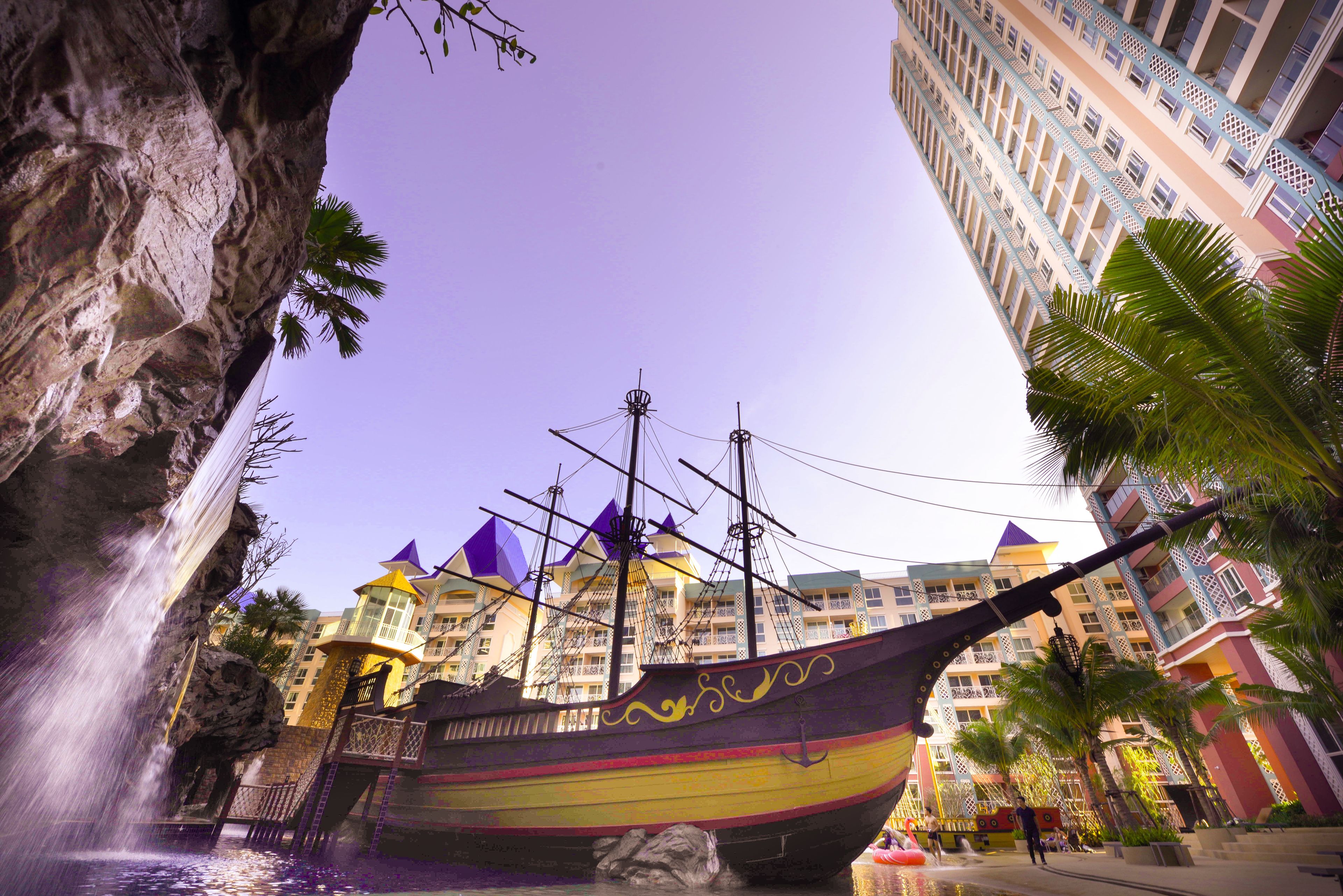 A large ship-shaped building with balconies and a waterfall in front.