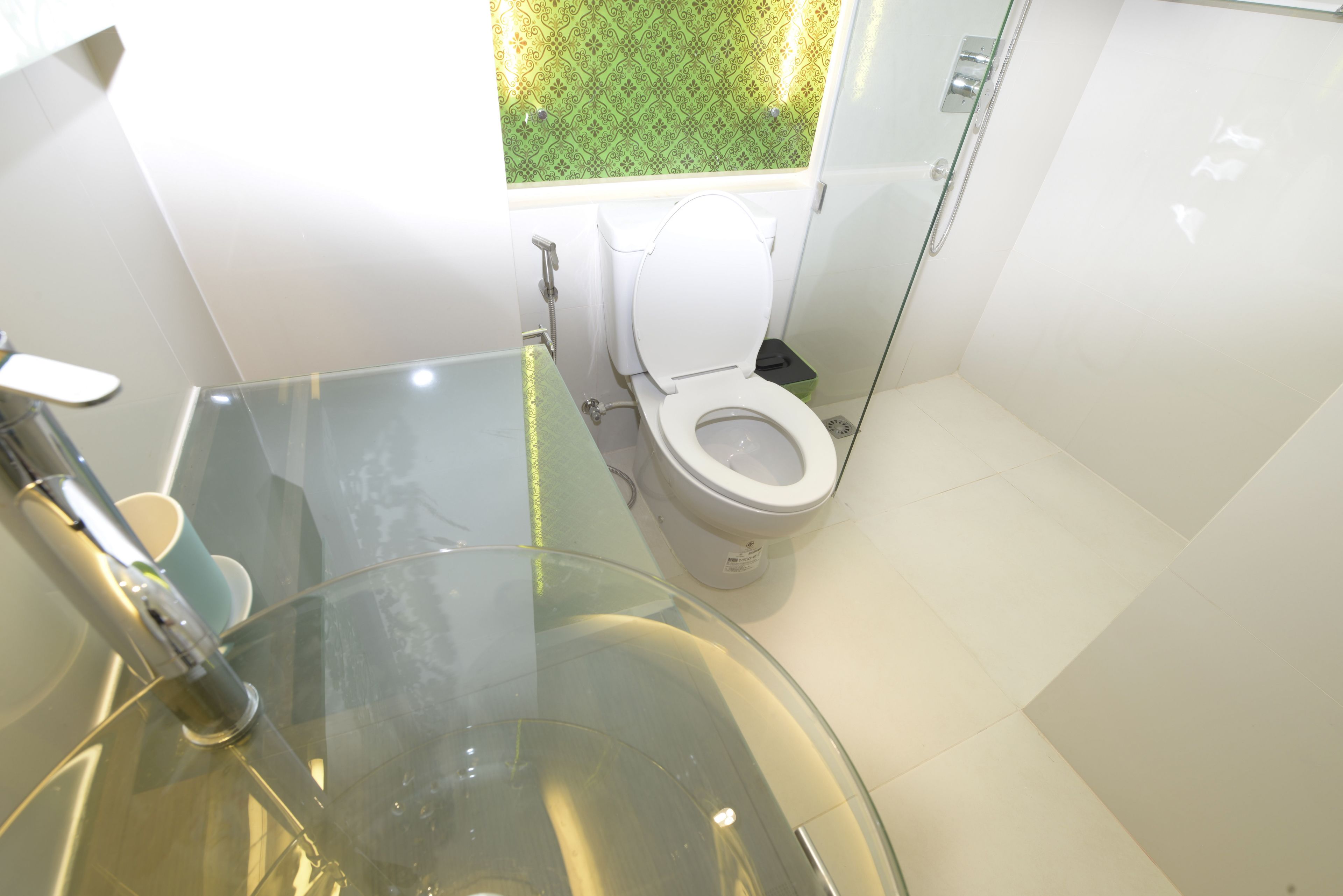 A modern bathroom with a glass sink, a toilet, and a shower area.