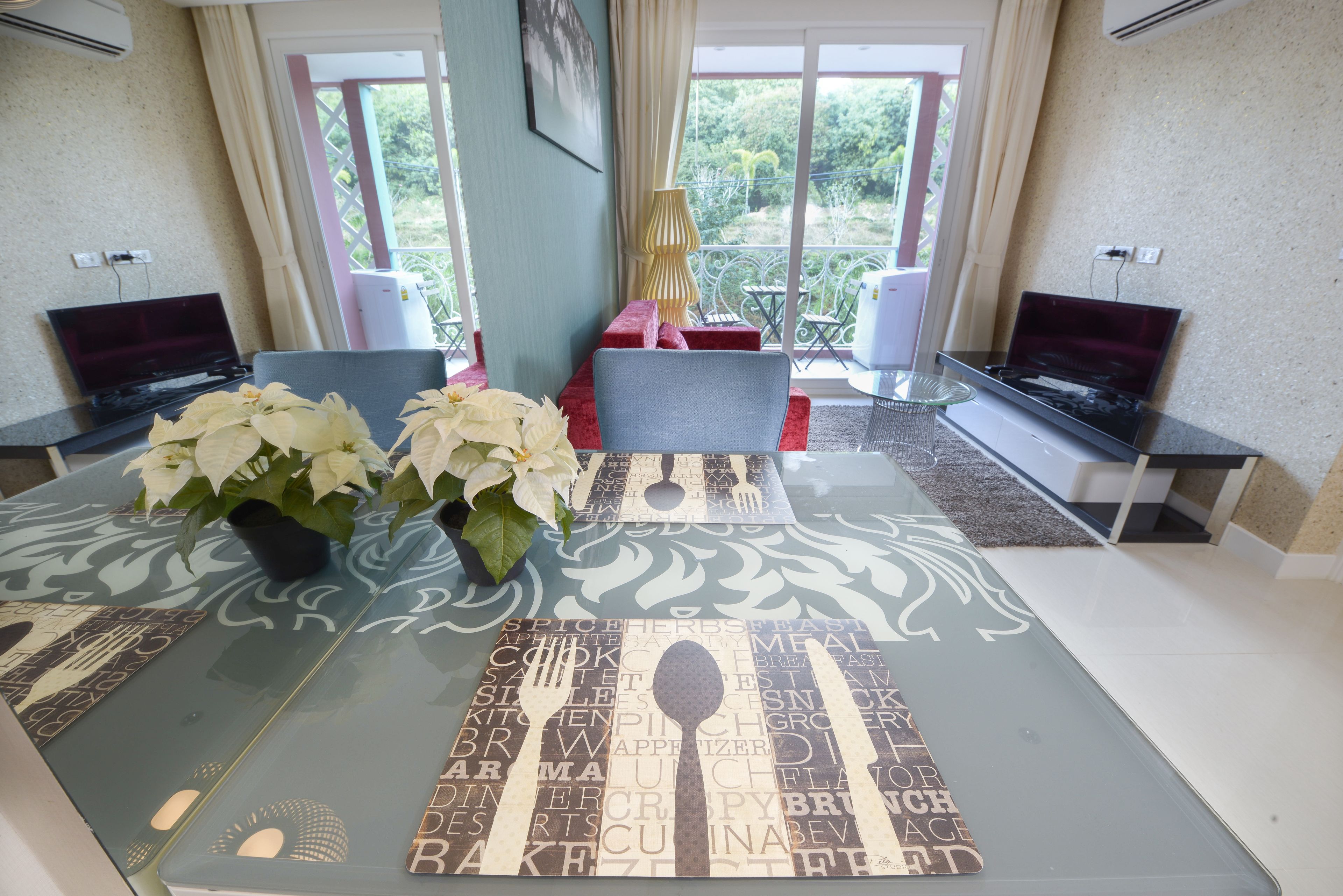 A dining area with a glass table, two chairs, and a vase with white flowers.