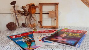 A table with magazines, a wooden frame, and decorative items. - Yahu Hotel (Zhuqi)