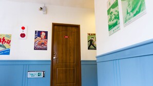 A hallway with a wooden door marked with the number 305, blue wainscoting, and several posters on the walls. - Yahu Hotel (Zhuqi)