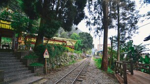 A railway track with a wooden bridge and stairs leading to a building with a yellow roof. - Yahu Hotel (Zhuqi)