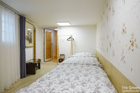 Un dormitorio con una cama, un banco de madera, una puerta y una pared con pintura descascarada.
