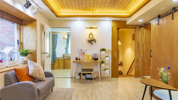 Una sala de estar moderna con techo de madera, un sofá, una mesa de comedor y una mesita.
