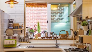 Una cocina moderna con pared de ladrillo, una ventana con vistas y diversos electrodomésticos y utensilios.