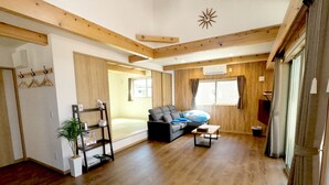 Ein geräumiges Wohnzimmer mit Holzboden, einer Couch, einem Couchtisch und einem großen Fenster.