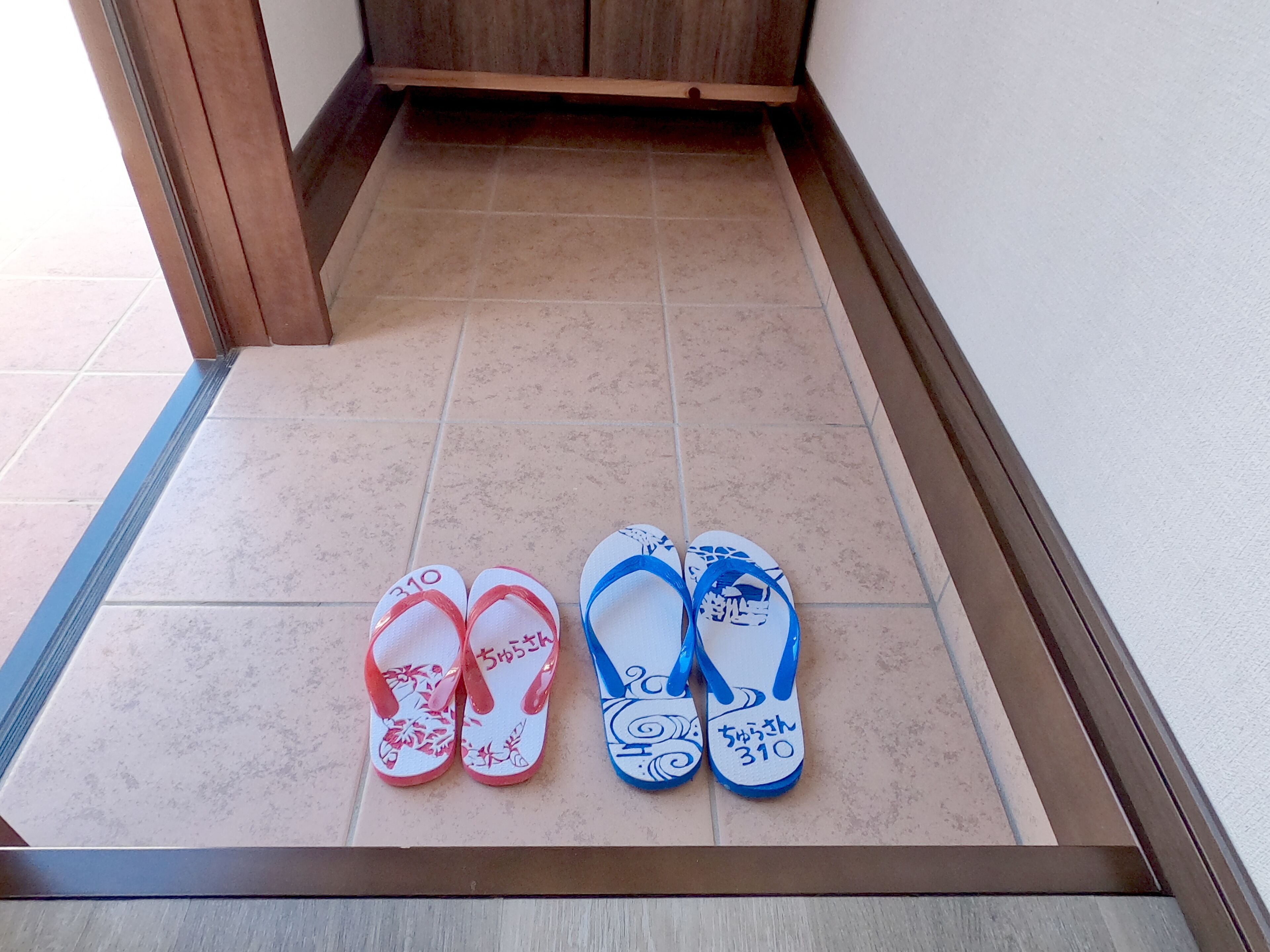 A pair of flip-flops with Japanese text on a tiled floor.
