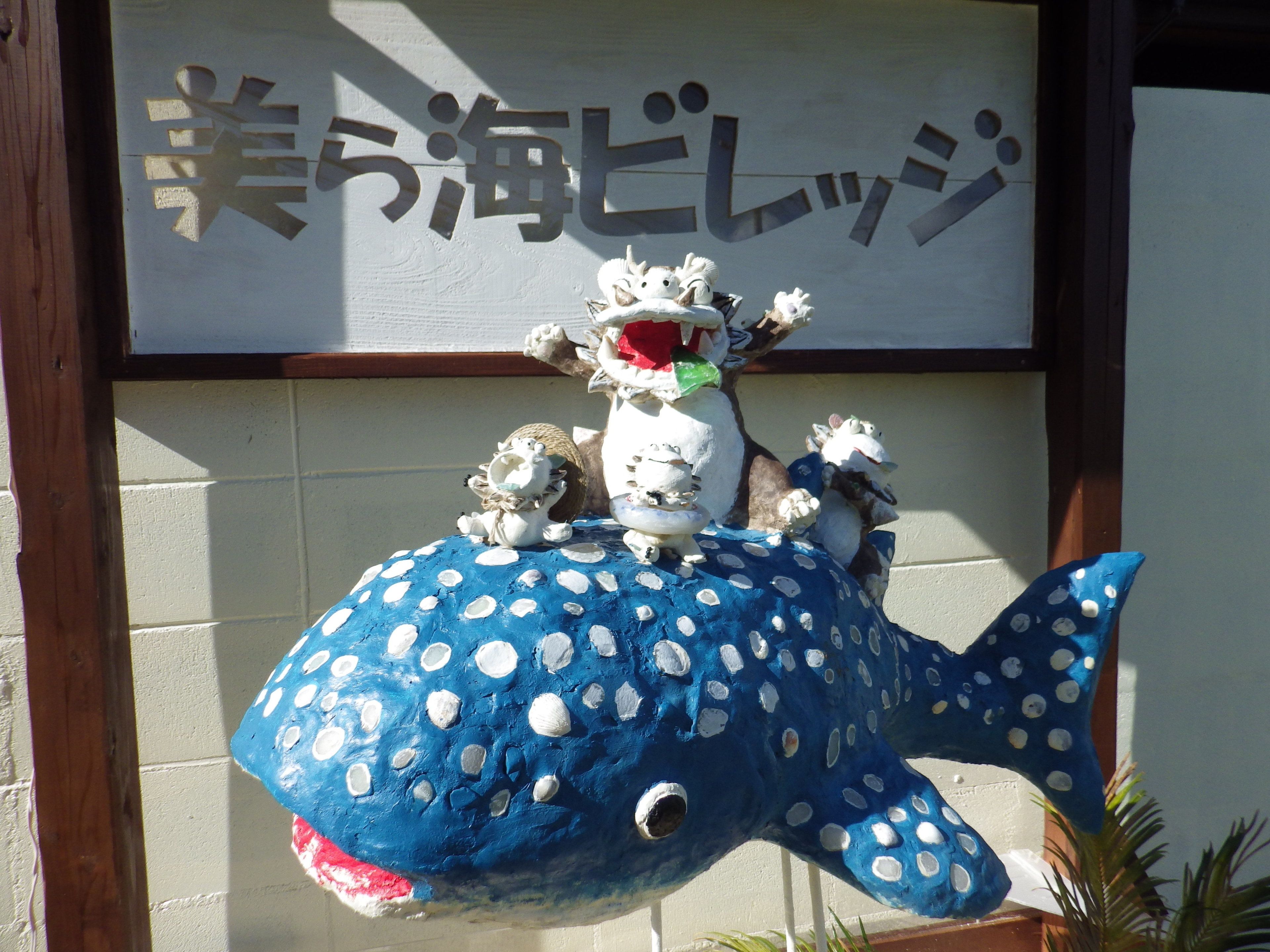 A large blue whale sculpture with polka dots and two small figures on top.