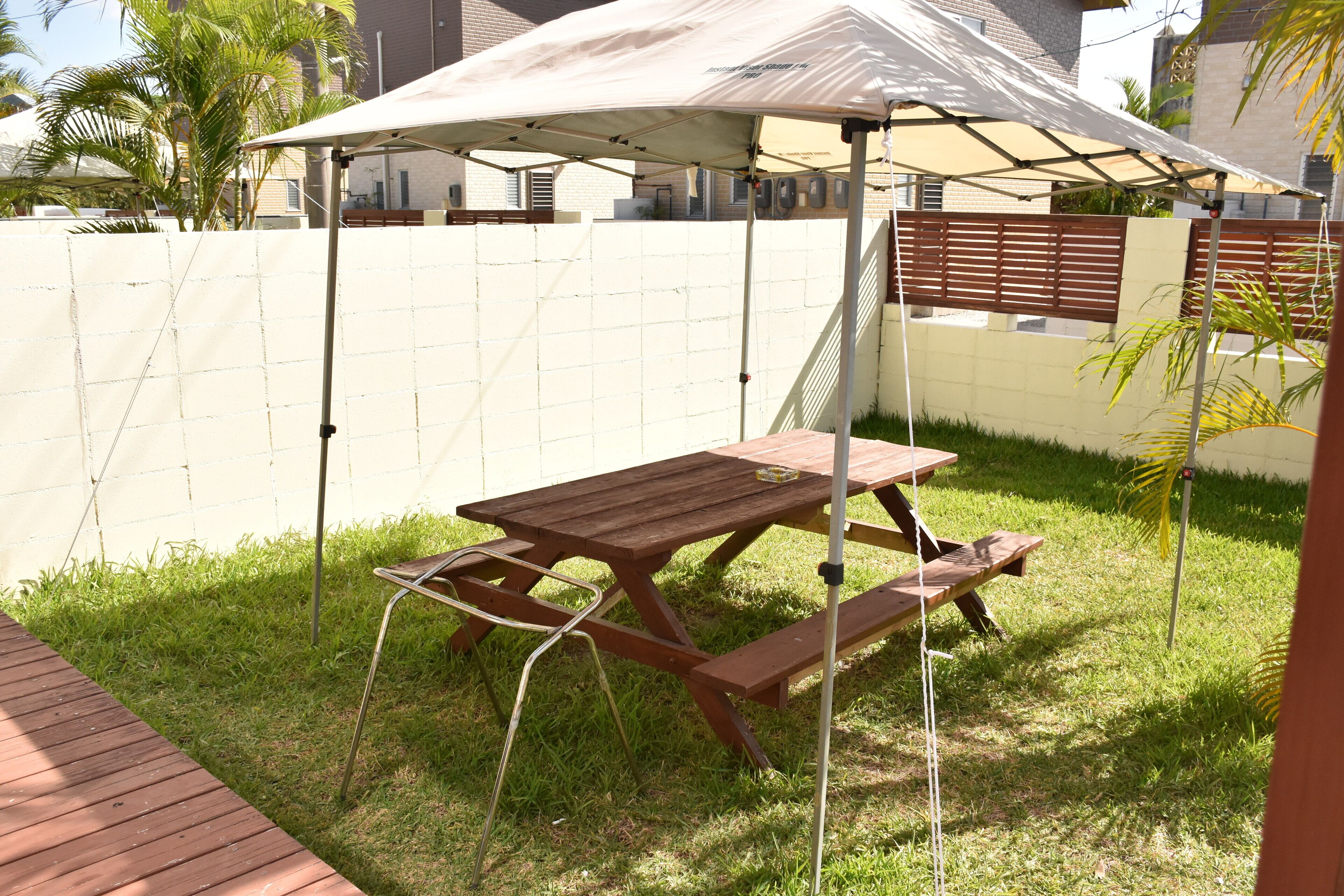 A picnic table with benches, a canopy, and a grassy area with a wooden deck.