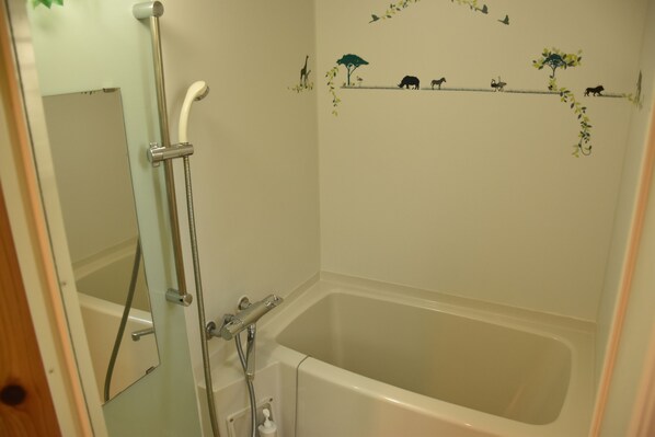 A bathroom with a bathtub, a shower, and a mirror.