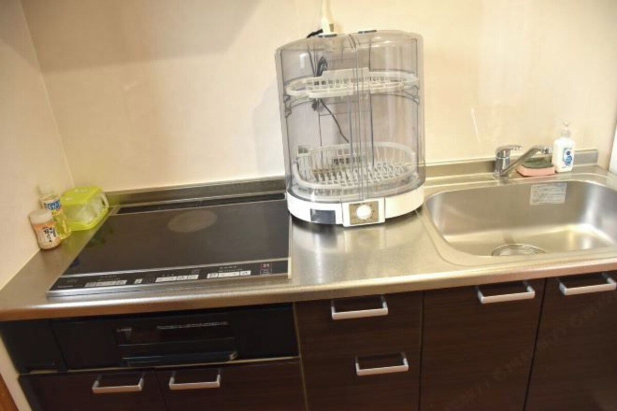 A kitchen with a built-in dishwasher, a sink, and a transparent water dispenser.