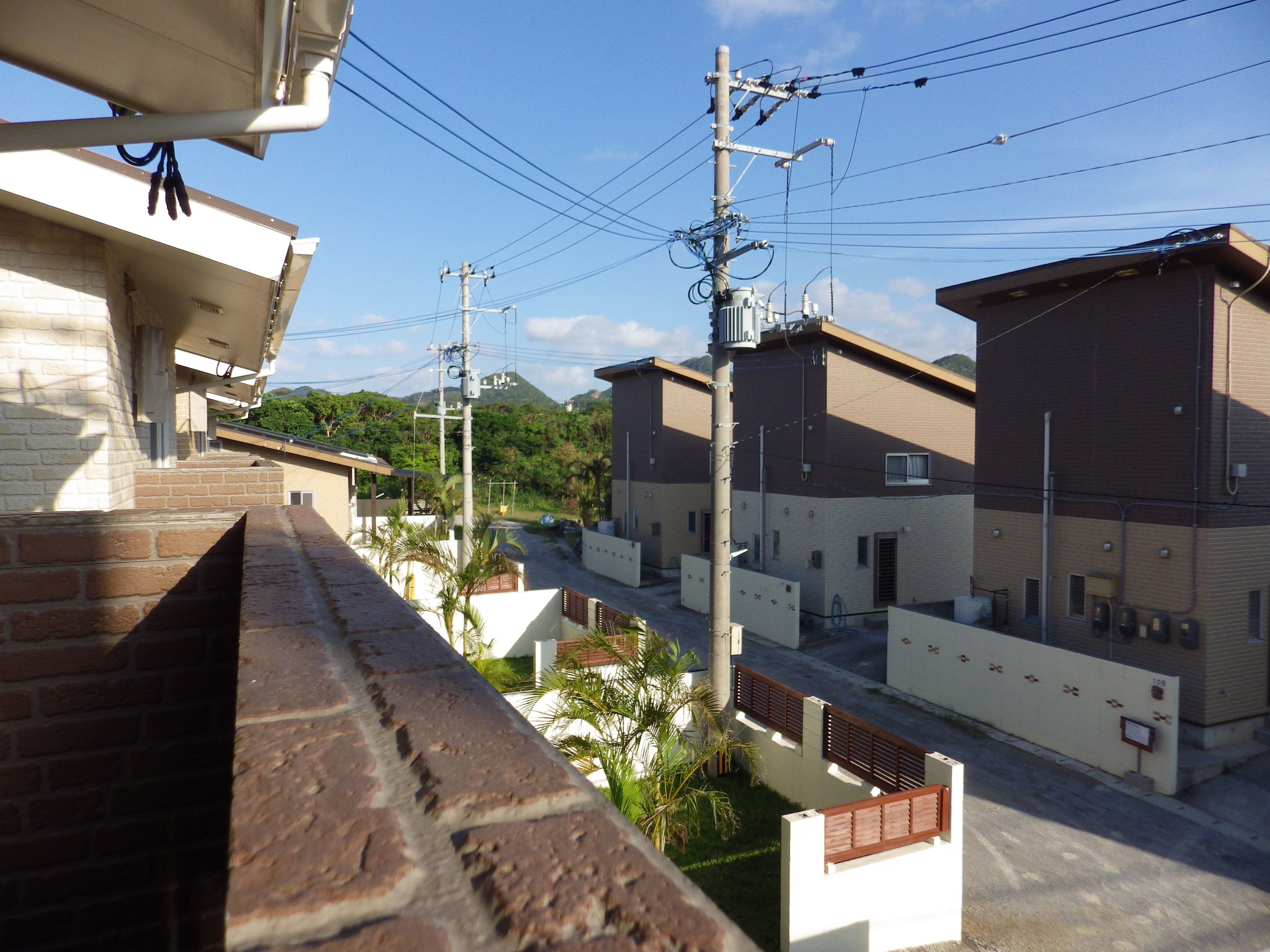 A residential area with brick buildings, power lines, and a mountain in the background.