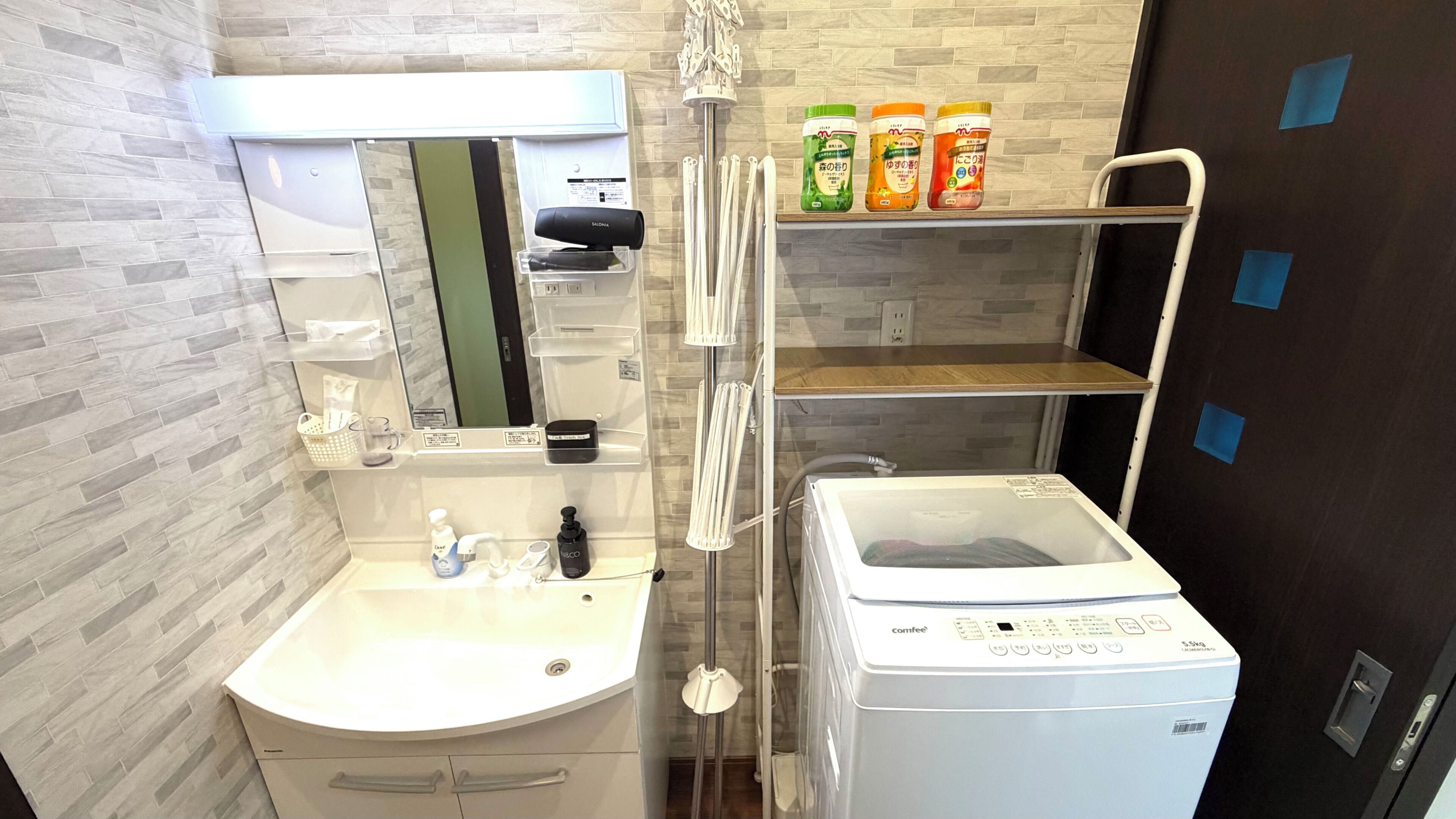 A bathroom with a sink, mirror, towel rack, and a Comfee washing machine.
