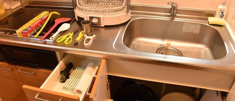 A kitchen with a stainless steel sink, a toaster, a blender, and various utensils.