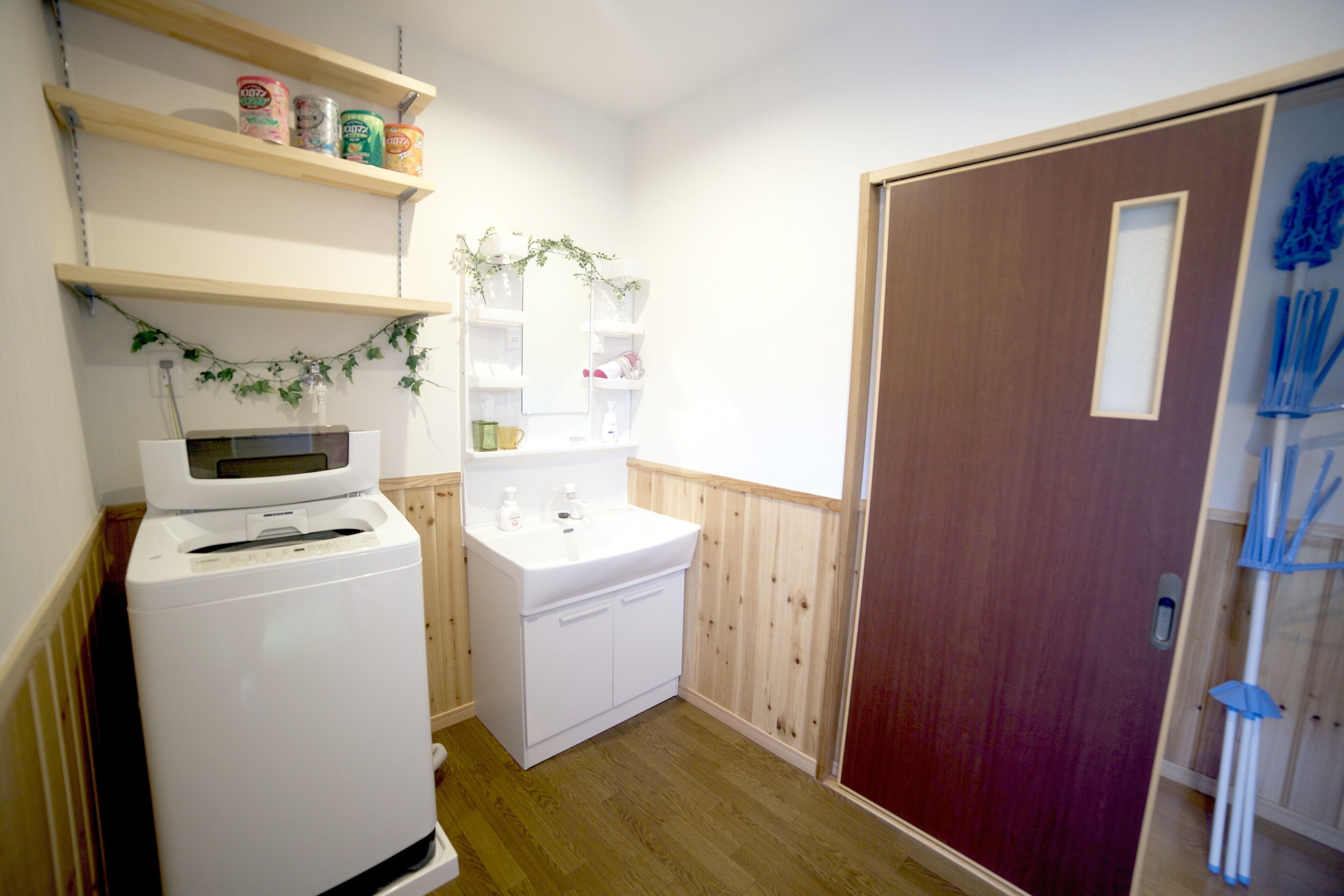 A compact laundry room with a washing machine, a dryer, and shelves with toiletries.