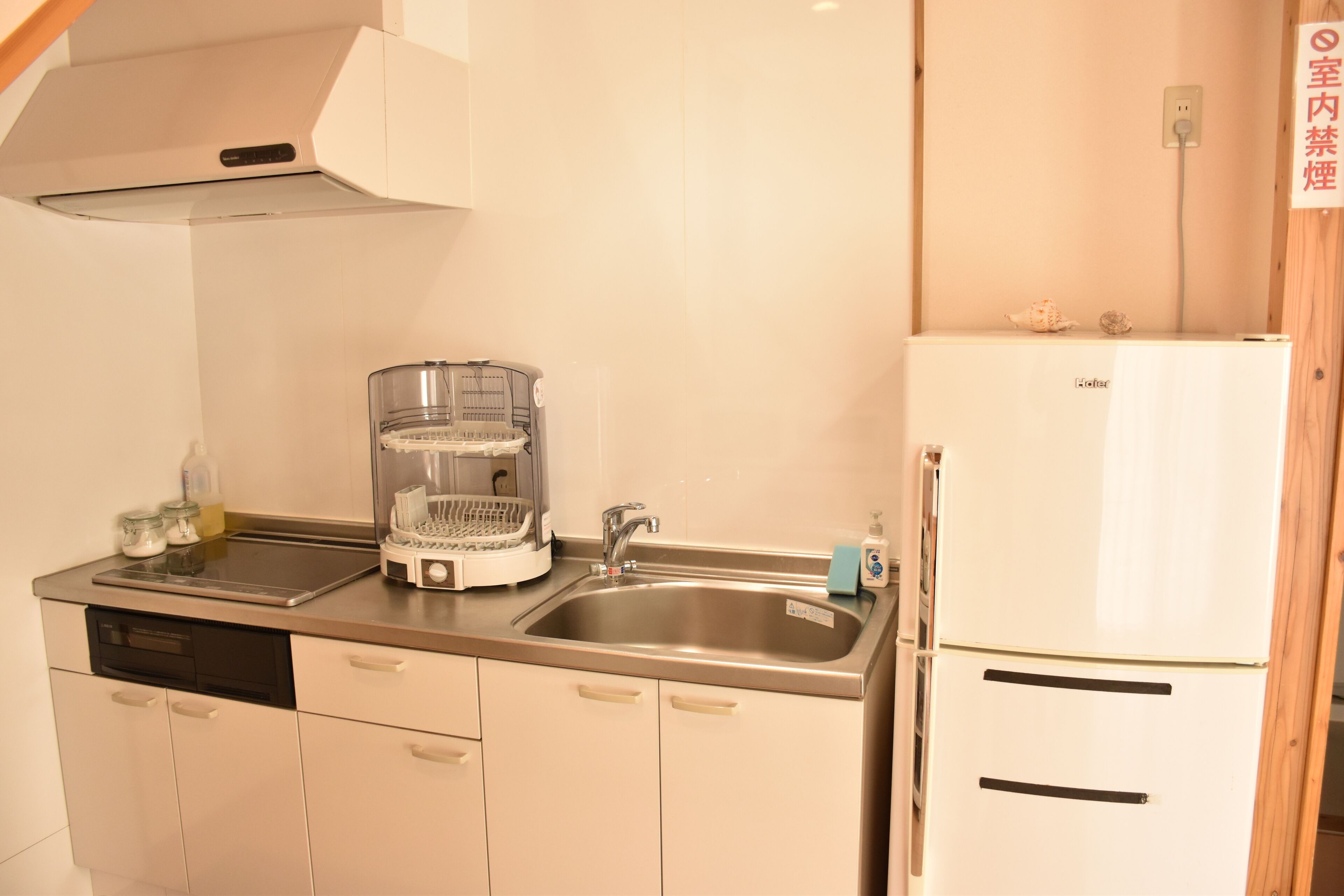 A kitchen with a dishwasher, a coffee maker, a sink, and a refrigerator.
