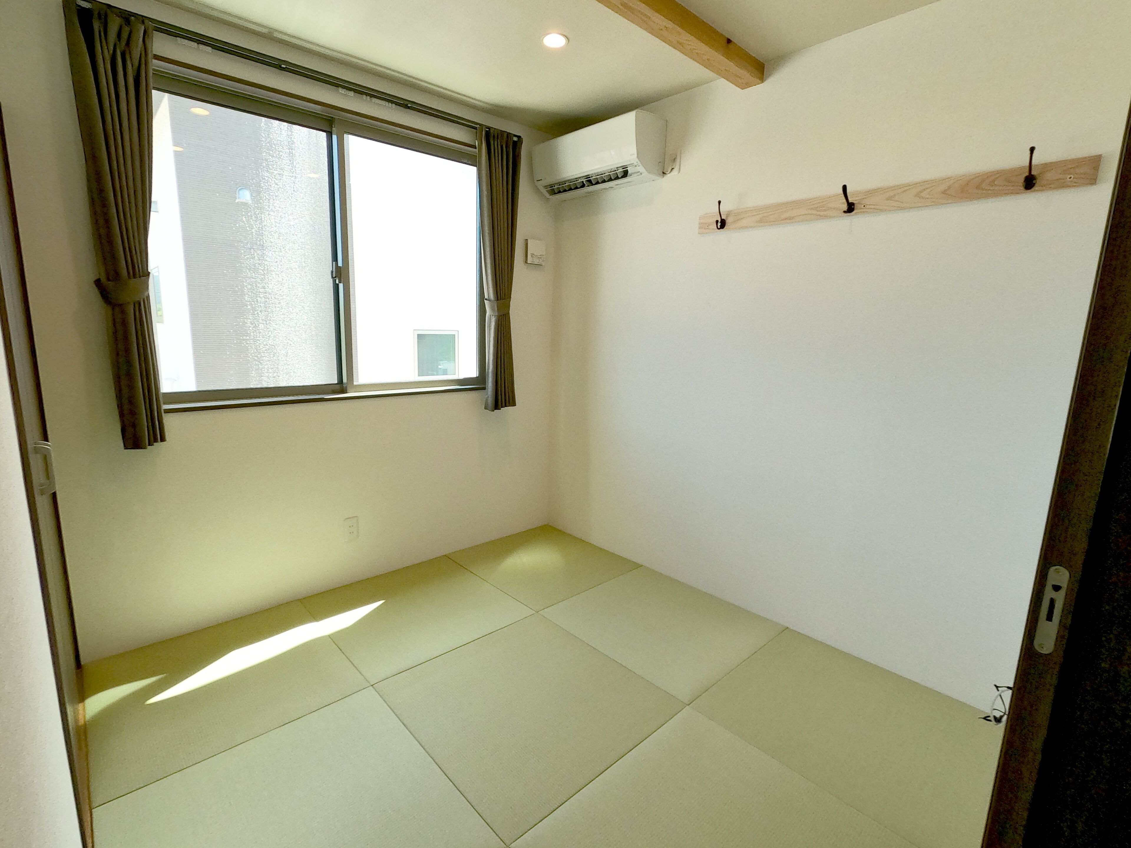 Une pièce dotée d’une grande fenêtre, d’un ventilateur de plafond et d’un interrupteur sur le mur.