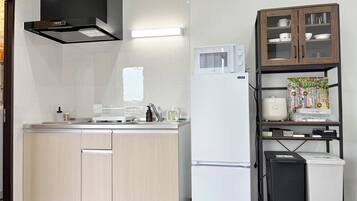 Una cocina moderna con microondas integrado, un refrigerador blanco y un armario de madera con puertas de cristal.