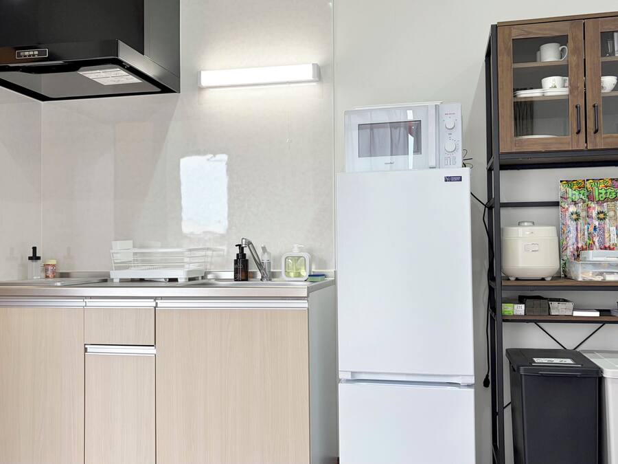Una cocina moderna con microondas integrado, un refrigerador blanco y un armario de madera con puertas de cristal.