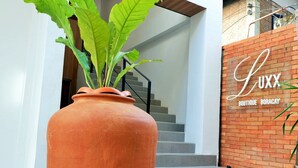 A large terracotta pot with green foliage in front of a building with a sign reading "LUXX Boutique Boracay". - Luxx Boutique Boracay (Boracay Island)