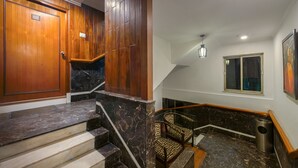 A staircase with marble steps and wooden walls, a door labeled '405', a small trash bin, and a chair. - Treebo Green View, Park Circus (Kolkata)