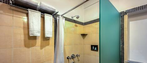 A bathroom with beige tiled walls, a shower area, and a green accent wall.
