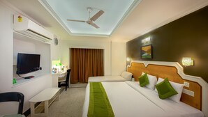 A hotel room with a bed, a desk, a television, and a ceiling fan. - Treebo Green View, Park Circus (Kolkata)
