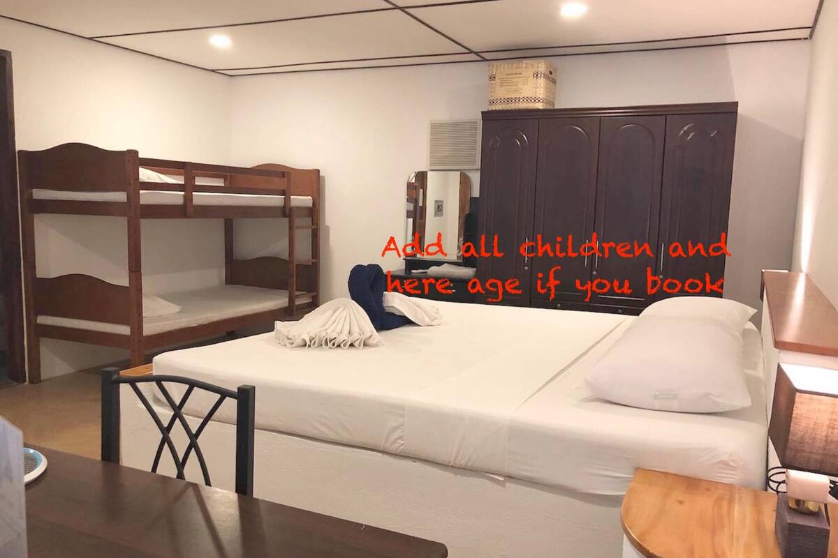 Um quarto com beliches, uma escrivaninha e um guarda-roupa.