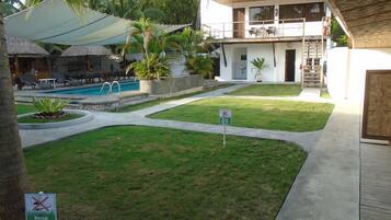 A pool area with lounge chairs and a sign indicating 'Keep Off The Grass'.