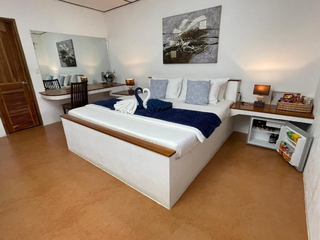 A modern bedroom with a large bed, a desk, and a mirror.