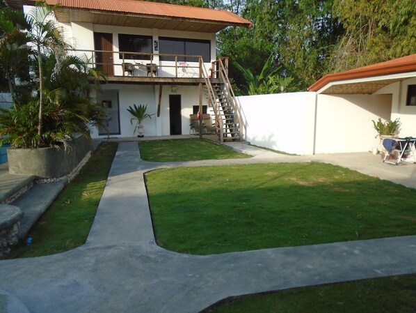 A two-story house with a balcony, a small patio, and a well-maintained lawn. - Parrot Resort Moalboal (Moalboal)
