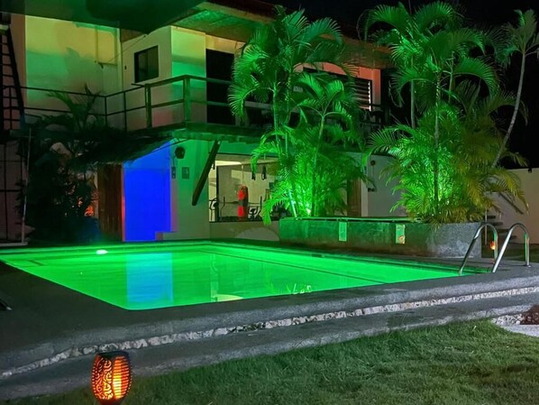 A swimming pool with surrounding palm trees and a building with a balcony. - Parrot Resort Moalboal (Moalboal)