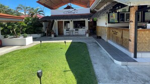 A building with a sign for a body massage service, a reception area, and a small outdoor seating area with a thatched roof. - Parrot Resort Moalboal (Moalboal)