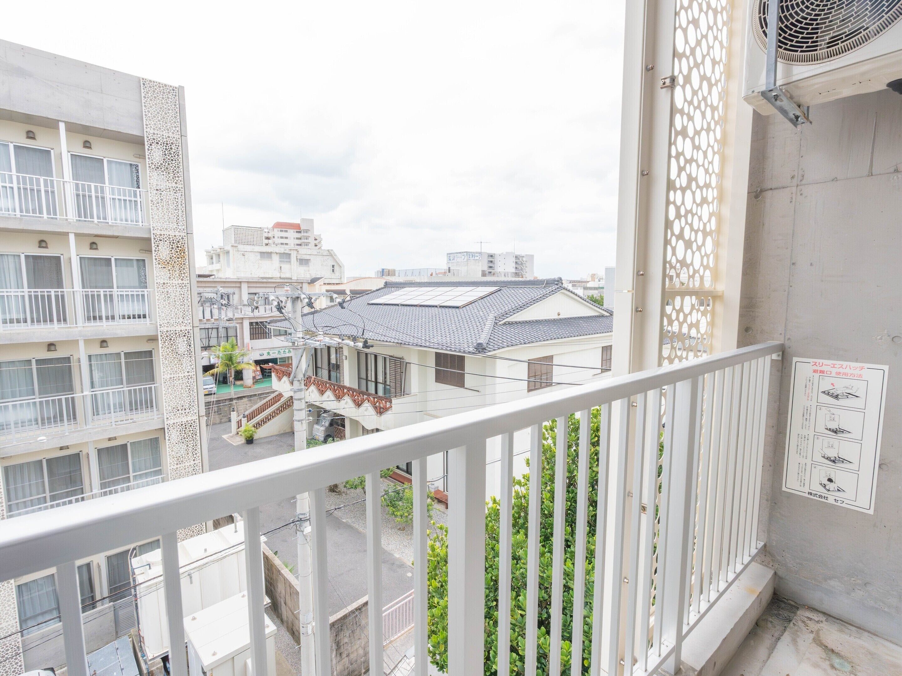 Un immeuble d’habitation doté d’un balcon, d’une balustrade blanche et d’une enseigne avec du texte en japonais.