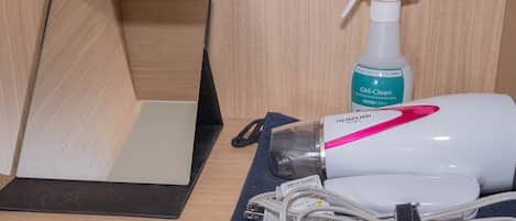A wooden cabinet with a mirror, a spray bottle, and a hairdryer on a blue cloth.