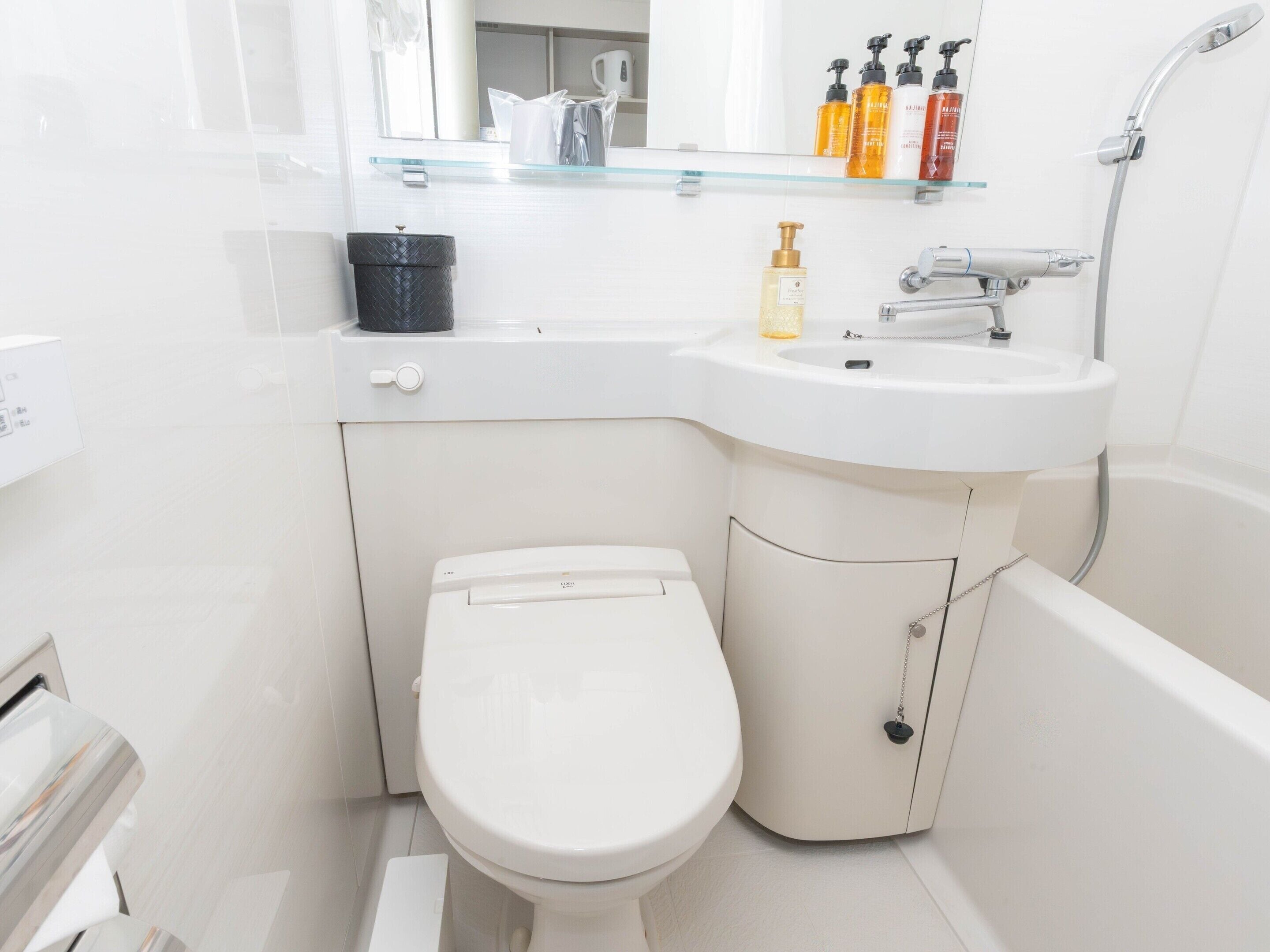 A compact bathroom with a toilet, a sink, and a shower.