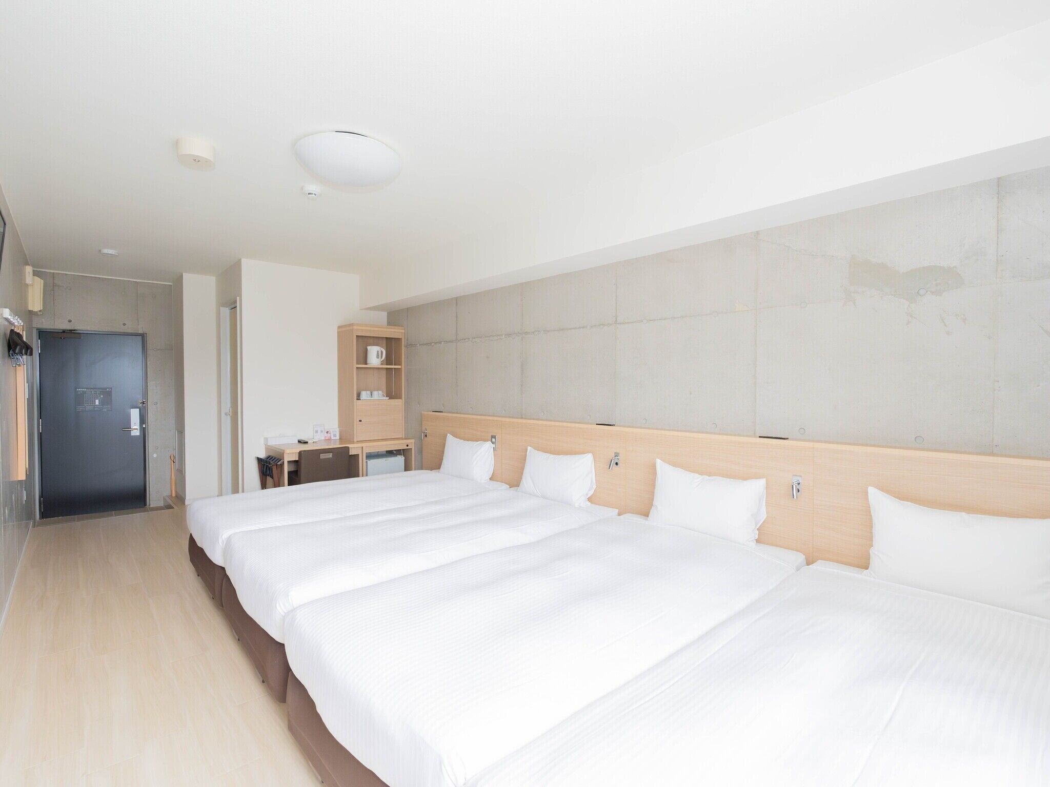 A hotel room with a large bed, a desk, a wardrobe, and a bathroom.
