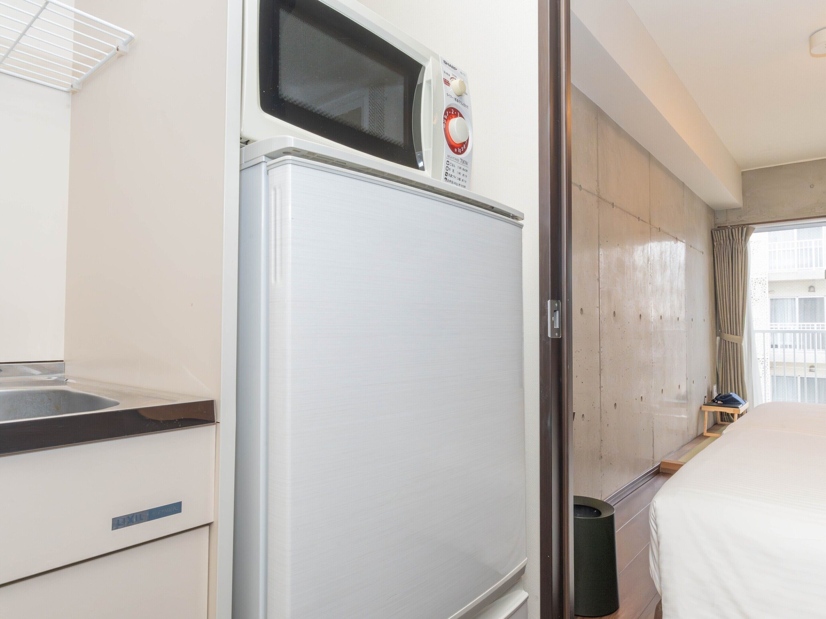 Una kitchenette compacta con microondas, un lavamanos pequeño y un armario.