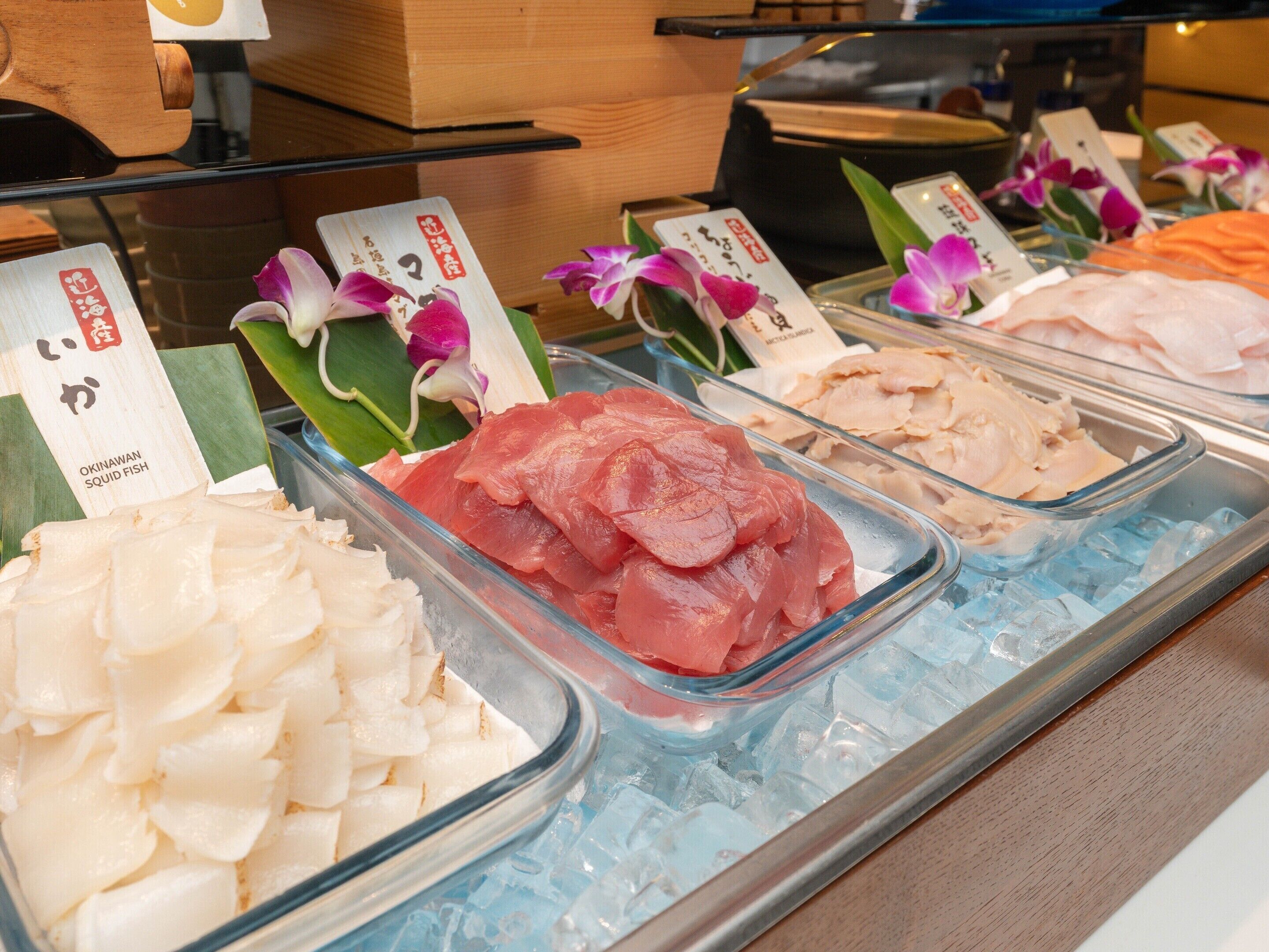 Una exhibición de mariscos con diferentes tipos de pescado, incluyendo sashimi, sobre hielo.