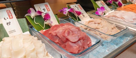 Una exhibición de mariscos con diferentes tipos de pescado, incluyendo sashimi, sobre hielo.